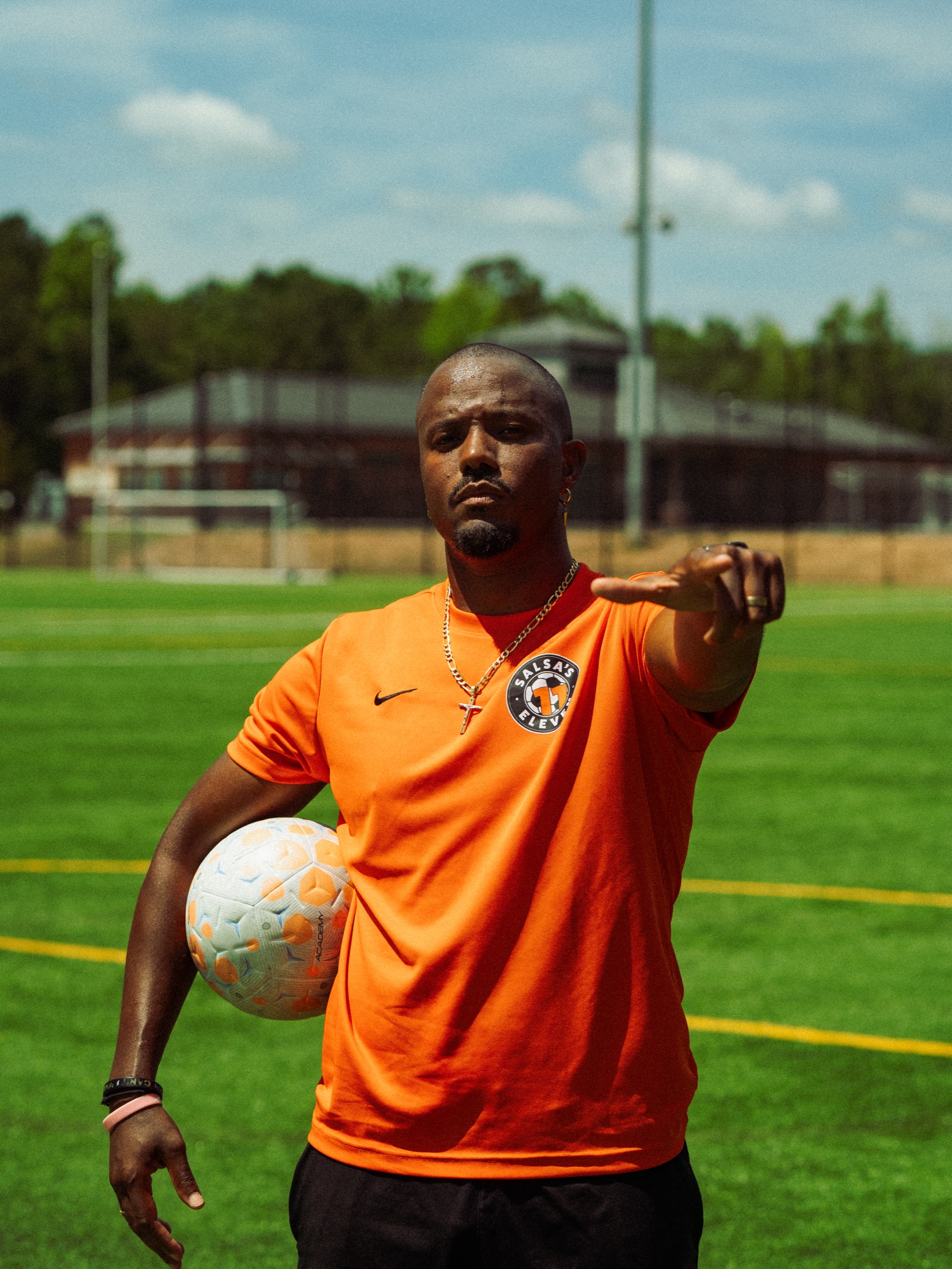 Coach Salsa on the field in orange, holding a soccer ball